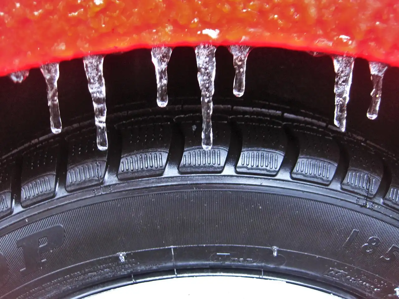 Mechanic inspecting a car with winter tires on one axle and all-season tires on the other.