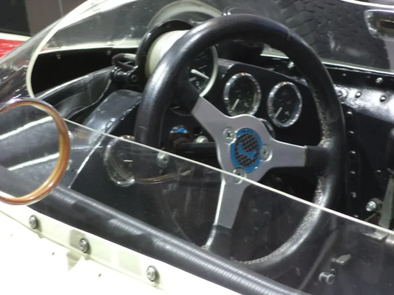 Motec C127 dash on a workbench with wiring harness, connectors, and laptop in a garage
