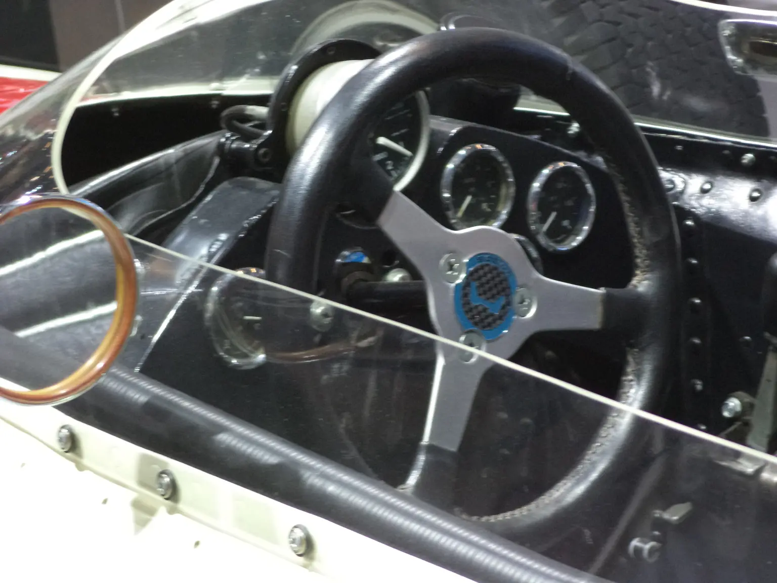 Technician wiring a Motec C127 dash connector with tools and loom on a bench