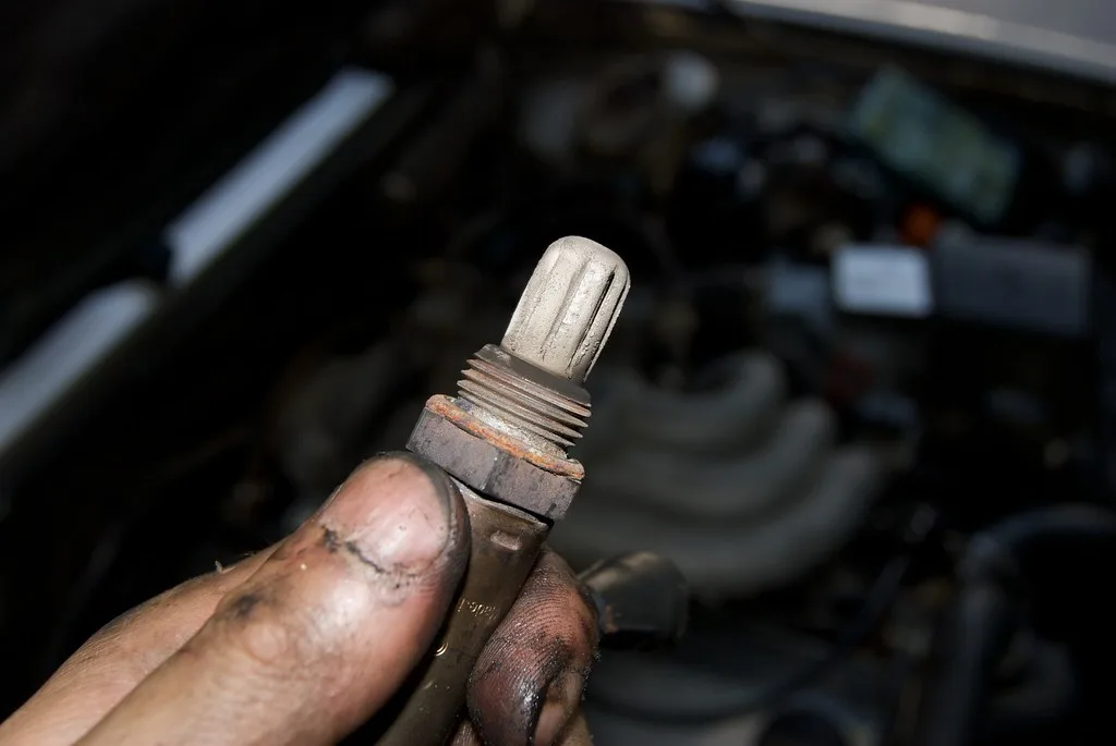 Mechanic comparing two oxygen sensors on a workbench in an auto repair bay