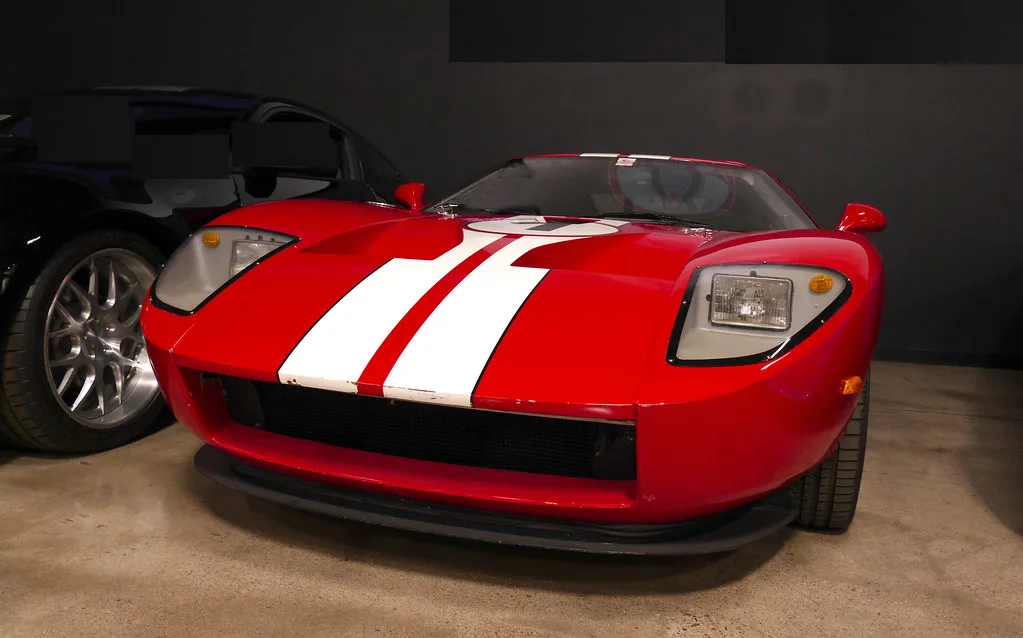 A sleek blue-and-silver race car beside calendars in a sunlit garage, with hands pointing at the dates.