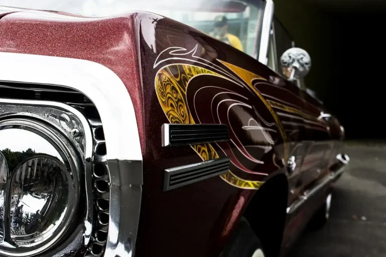 A person applying pinstripe decals to a sedan in daylight