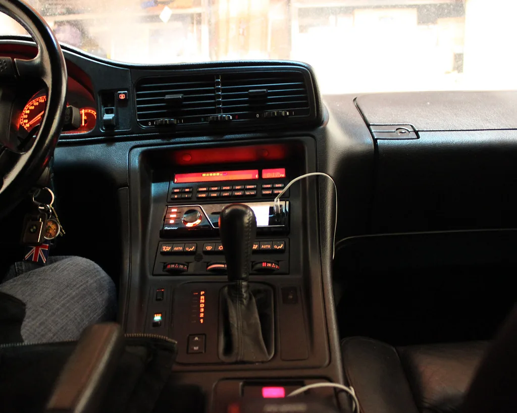 Hand plugging a phone into a Pioneer car stereo via USB in a dashboard close-up