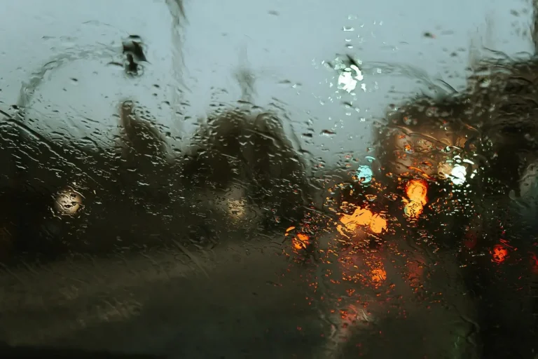 Driver holding a red Prestone windshield de-icer beside a frosted car windshield on a snowy morning
