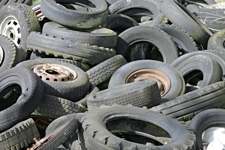 Winter tires stacked in a shop while a mechanic talks with a customer near the storage racks