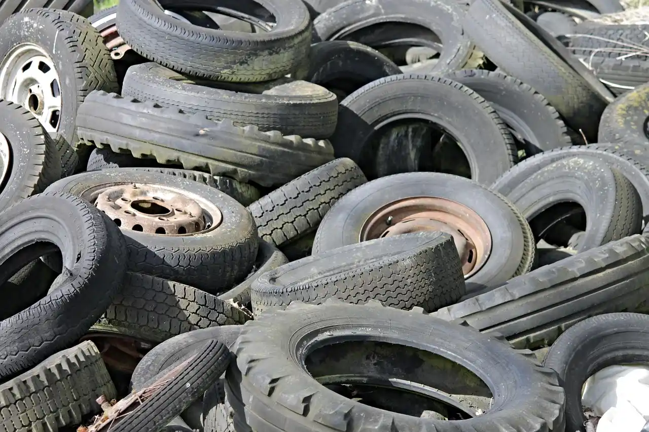 Winter tires stacked in a shop while a mechanic talks with a customer near the storage racks