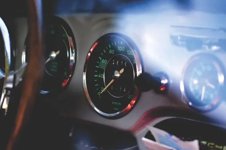 Driver comparing a car speedometer cluster with a GPS app on the dashboard