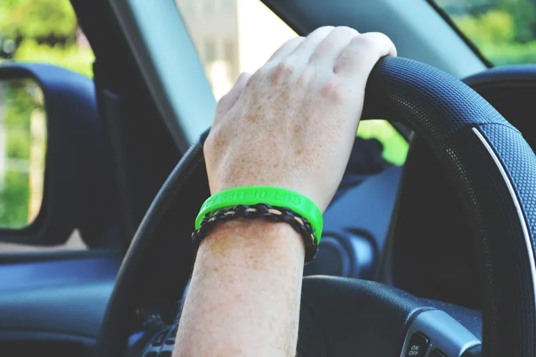 Car interior with a stitched steering wheel cover on the wheel in natural daylight