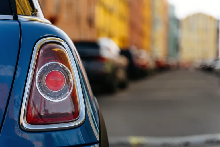 Mechanic inspecting a sedan's rear car lights and clear sticker placement area