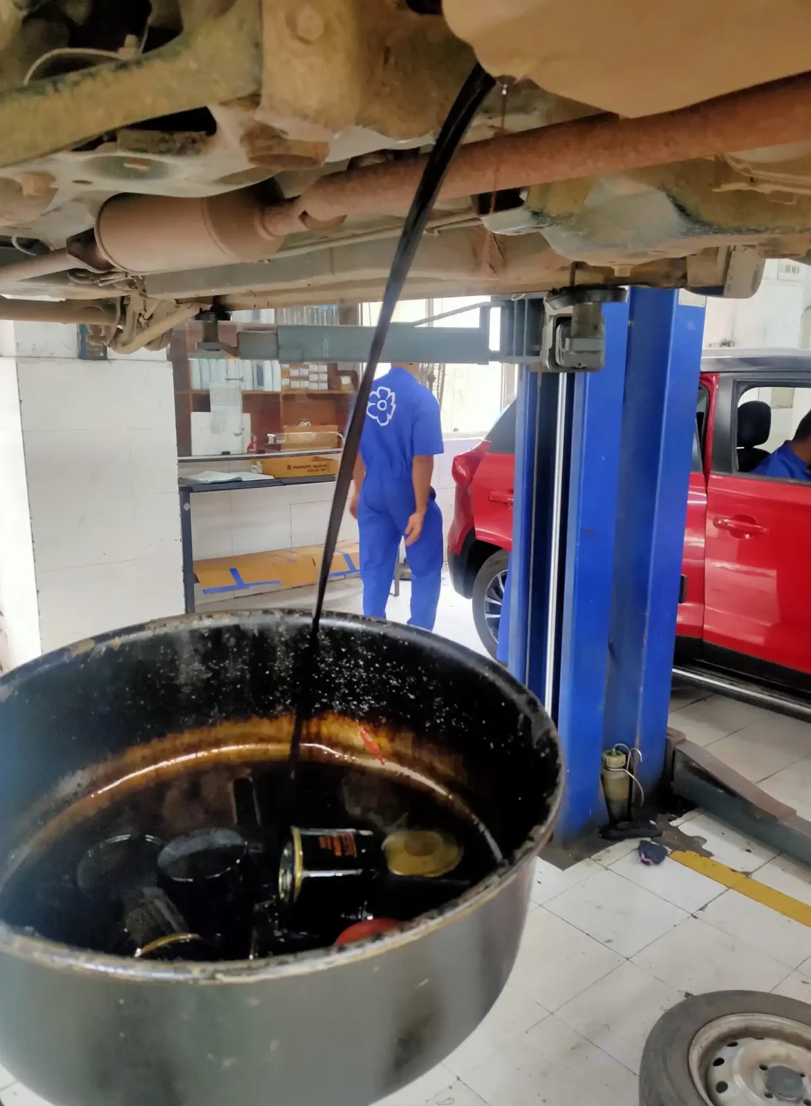 Hands install a reusable air filter on a car near tools and washable shop towels.