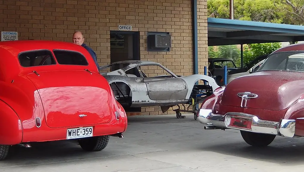 Hands sanding a vintage car body panel during automotive restoration