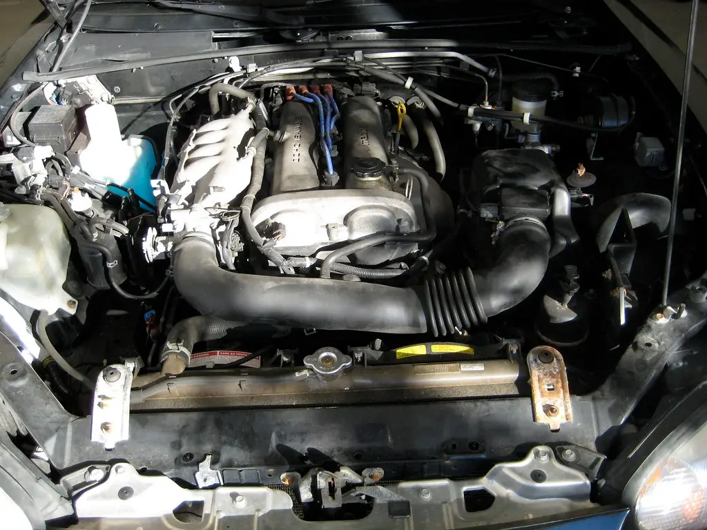 Gloved hands inspect a dirty throttle body bore with visible carbon buildup