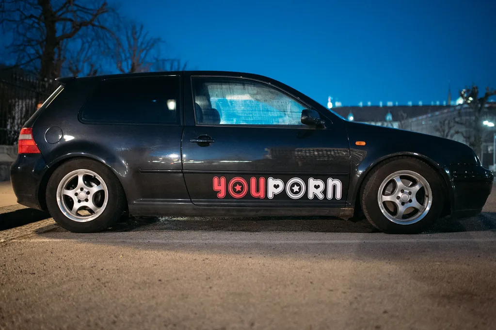 Close-up of a car doorjamb sticker being checked by hand with a flashlight