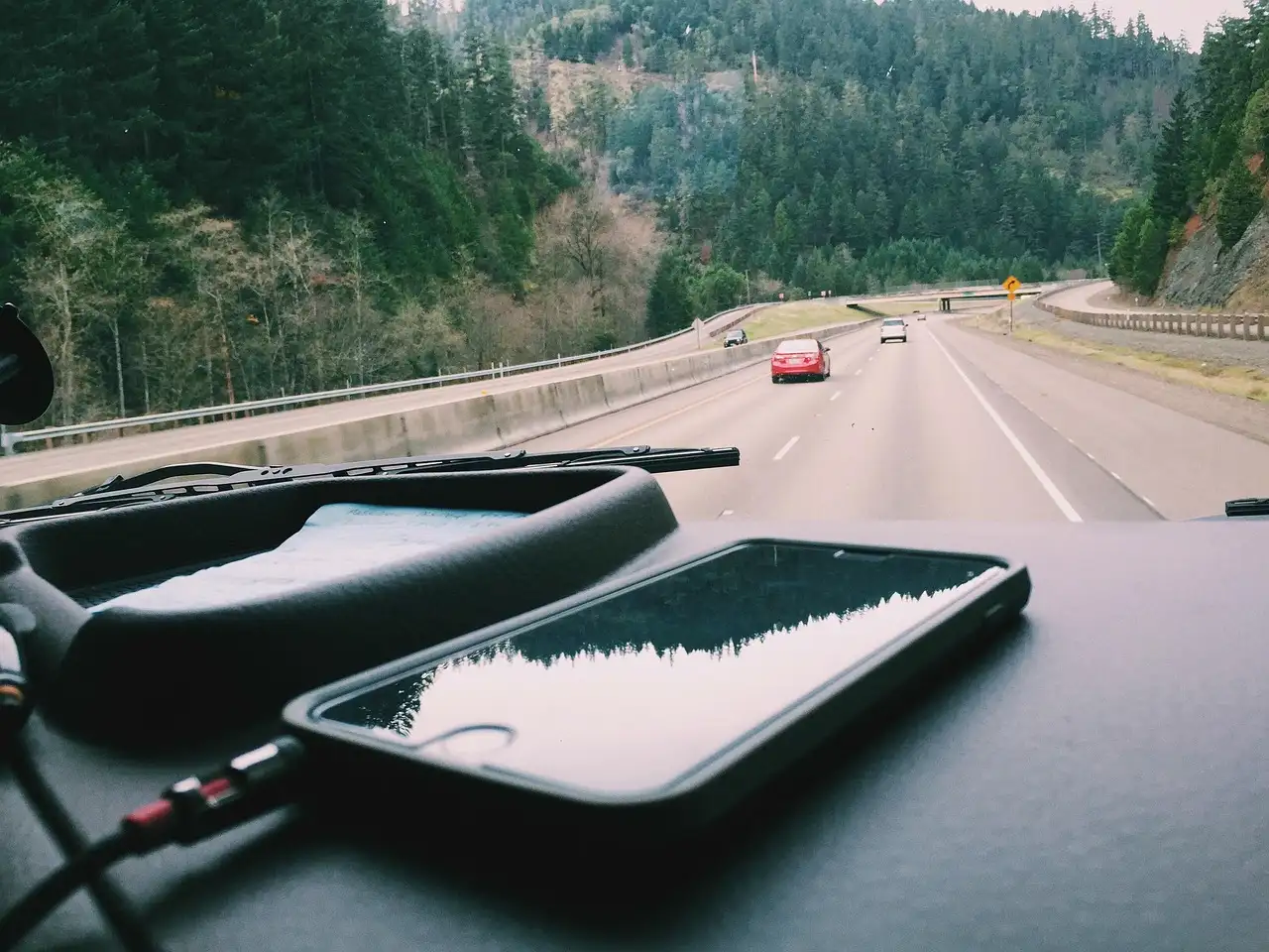 USB car chargers plugged into a car console with a phone and tablet charging in daylight