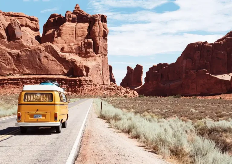 Traveler planning a world trip with maps and passport beside a classic touring car