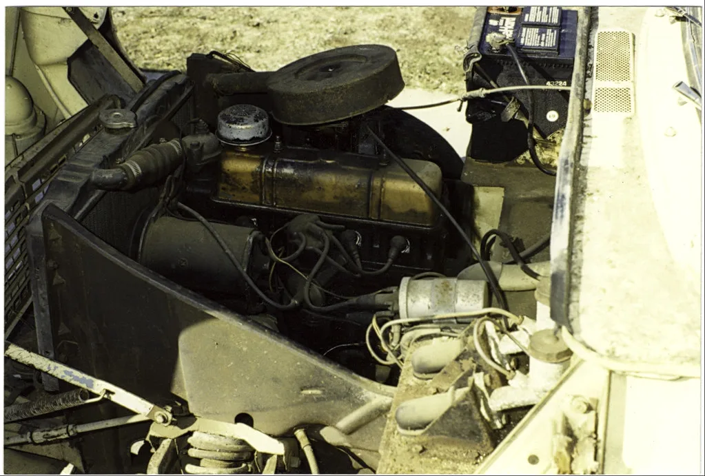Close-up of a coolant reservoir cap, service manual, and two orange coolant bottles on a garage bench
