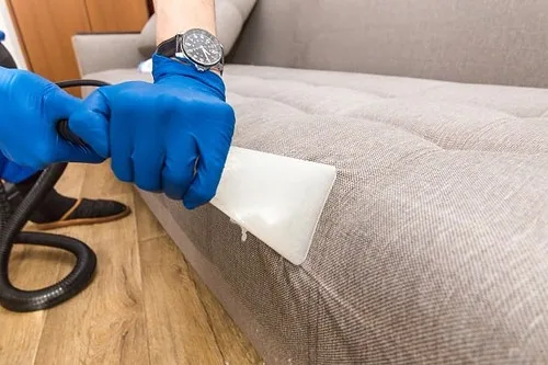 Microfiber cloth testing cleaner on a leather-look upholstery corner in natural light.