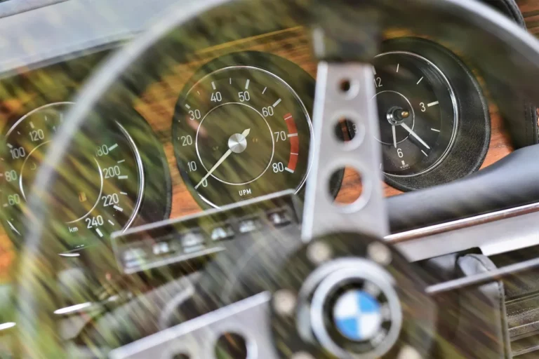 BMW sedan parked roadside with the driver looking at a dashboard warning.