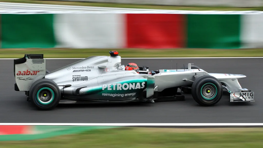 Close-up of a car rear wing and diffuser with racing tires in a pit lane.