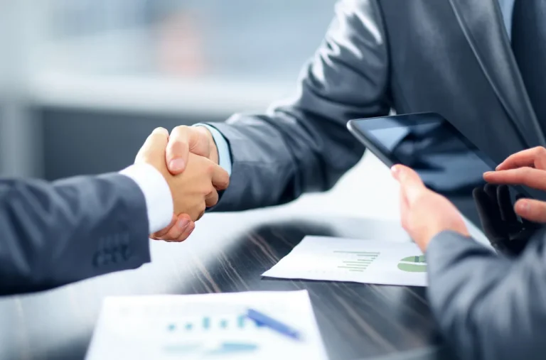 Buyer and salesperson reviewing car loan paperwork beside car keys in a bright dealership