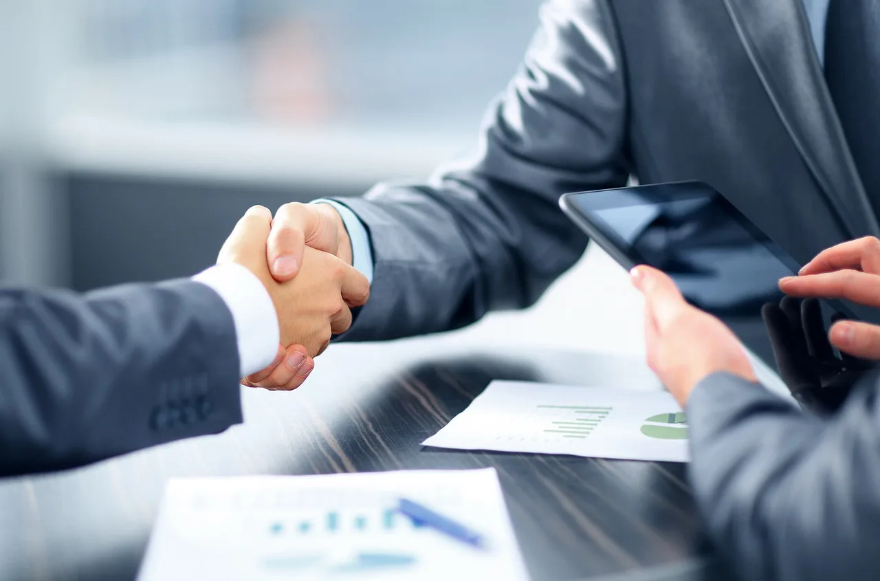 Buyer and salesperson reviewing car loan paperwork beside car keys in a bright dealership