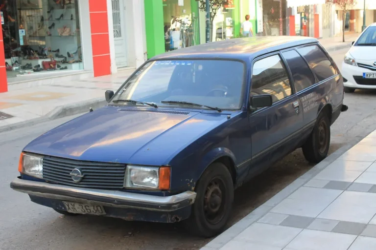 High-mileage sedan and hybrid SUV parked in a driveway with service records and a wrench nearby