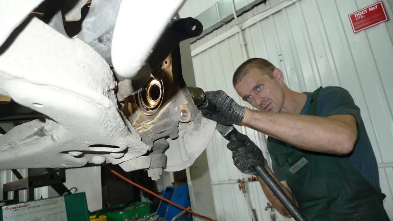Service car parked in a garage with a mechanic pointing at the open hood