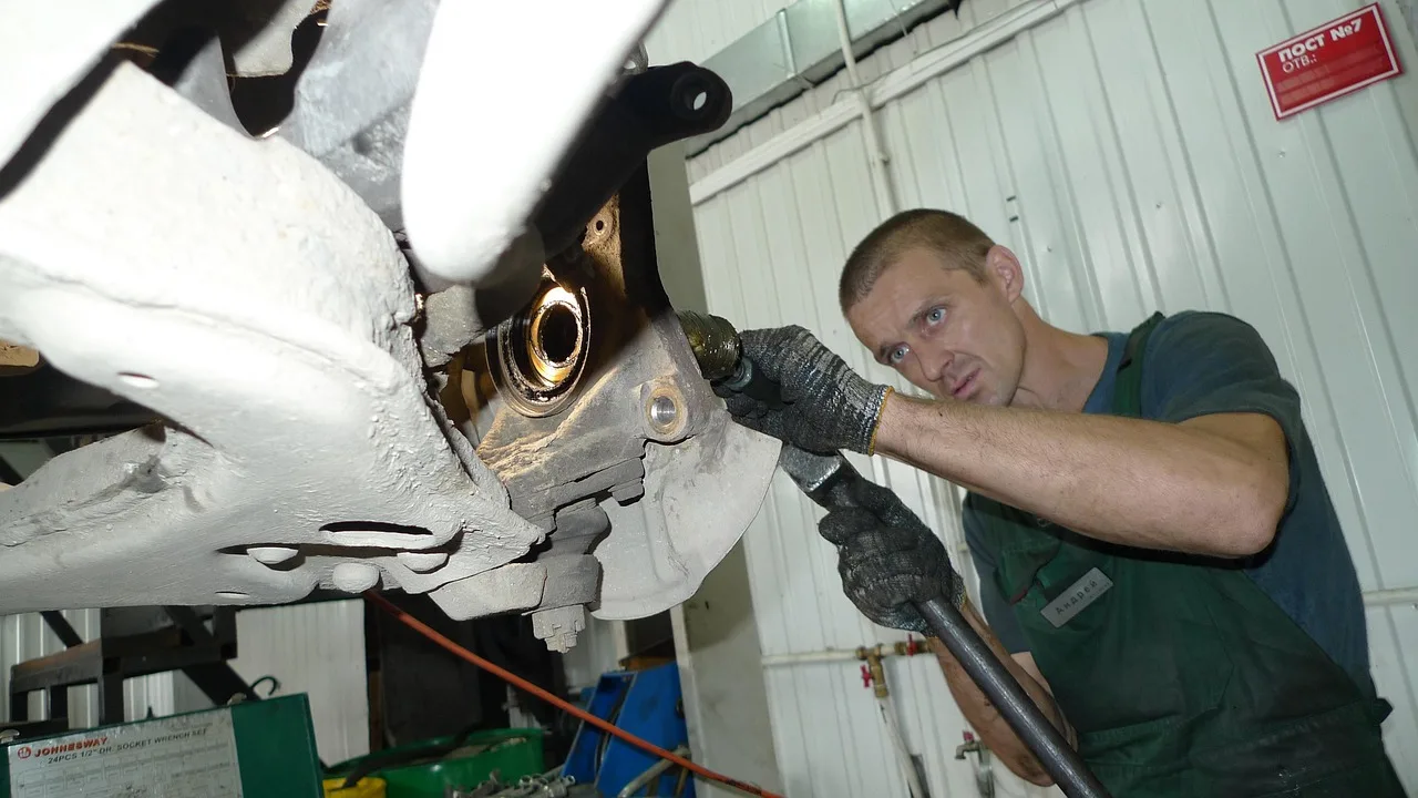 Service car parked in a garage with a mechanic pointing at the open hood