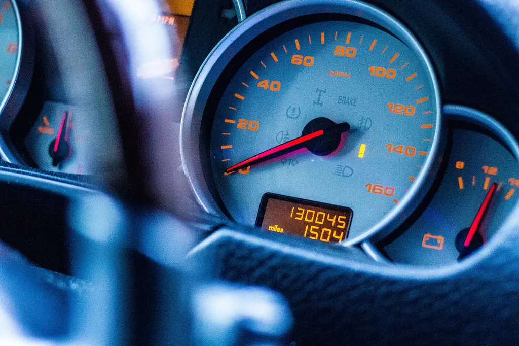 Used car buyer and mechanic inspecting a high-mileage sedan in daylight.