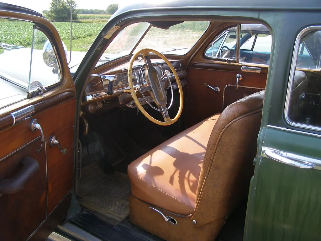 Close-up of a car door panel showing a manual window crank next to a power switch