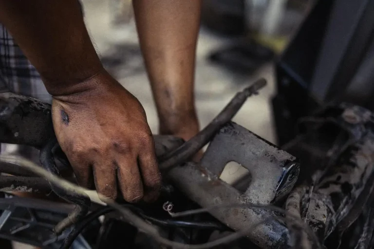 Customer and mechanic review a checklist beside a sedan outside a local car service shop