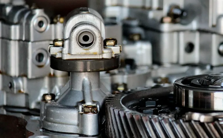 Mechanic pointing under a sedan to show where the transmission sits near the engine