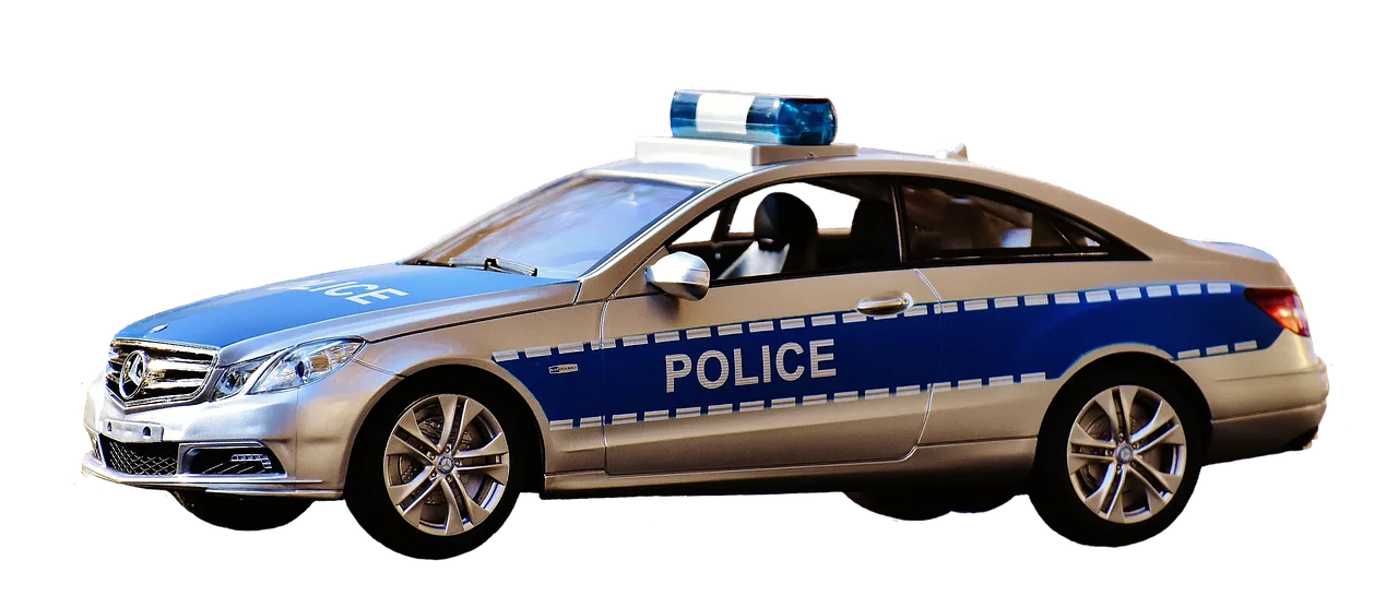 Police officer tapping a sedan trunk during a roadside stop at dusk