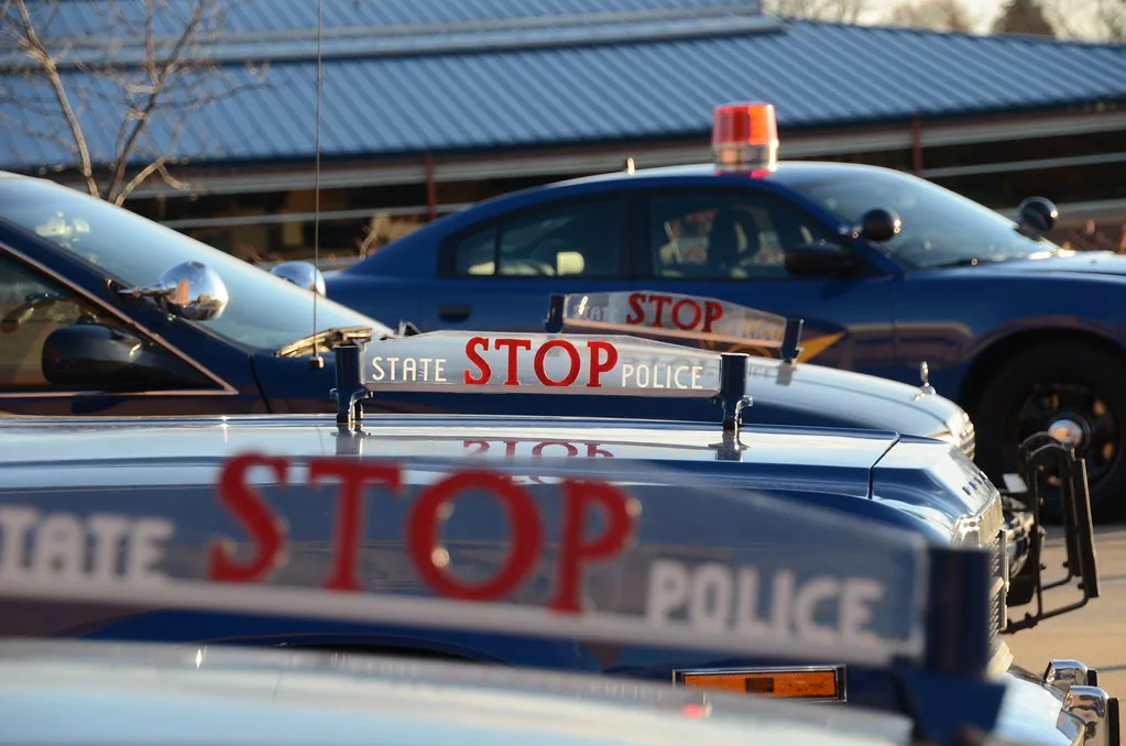 Gloved police hand tapping the edge of a car trunk beside a stopped vehicle